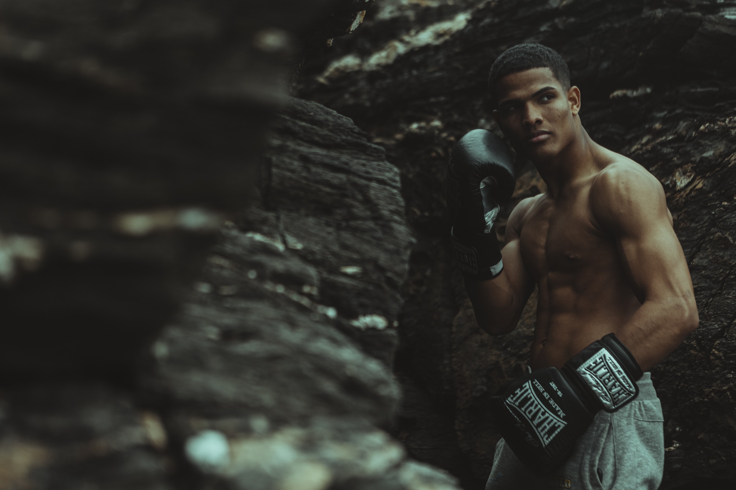 Retrato de un boxeador con guantes junto a las rocas